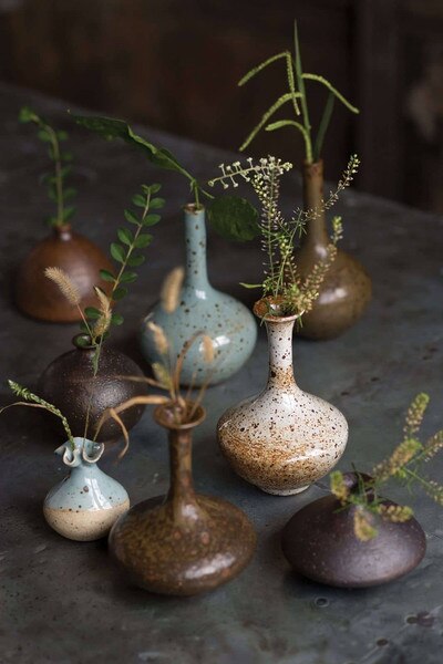 Brown and blue porcelain bud vases with flowers in them